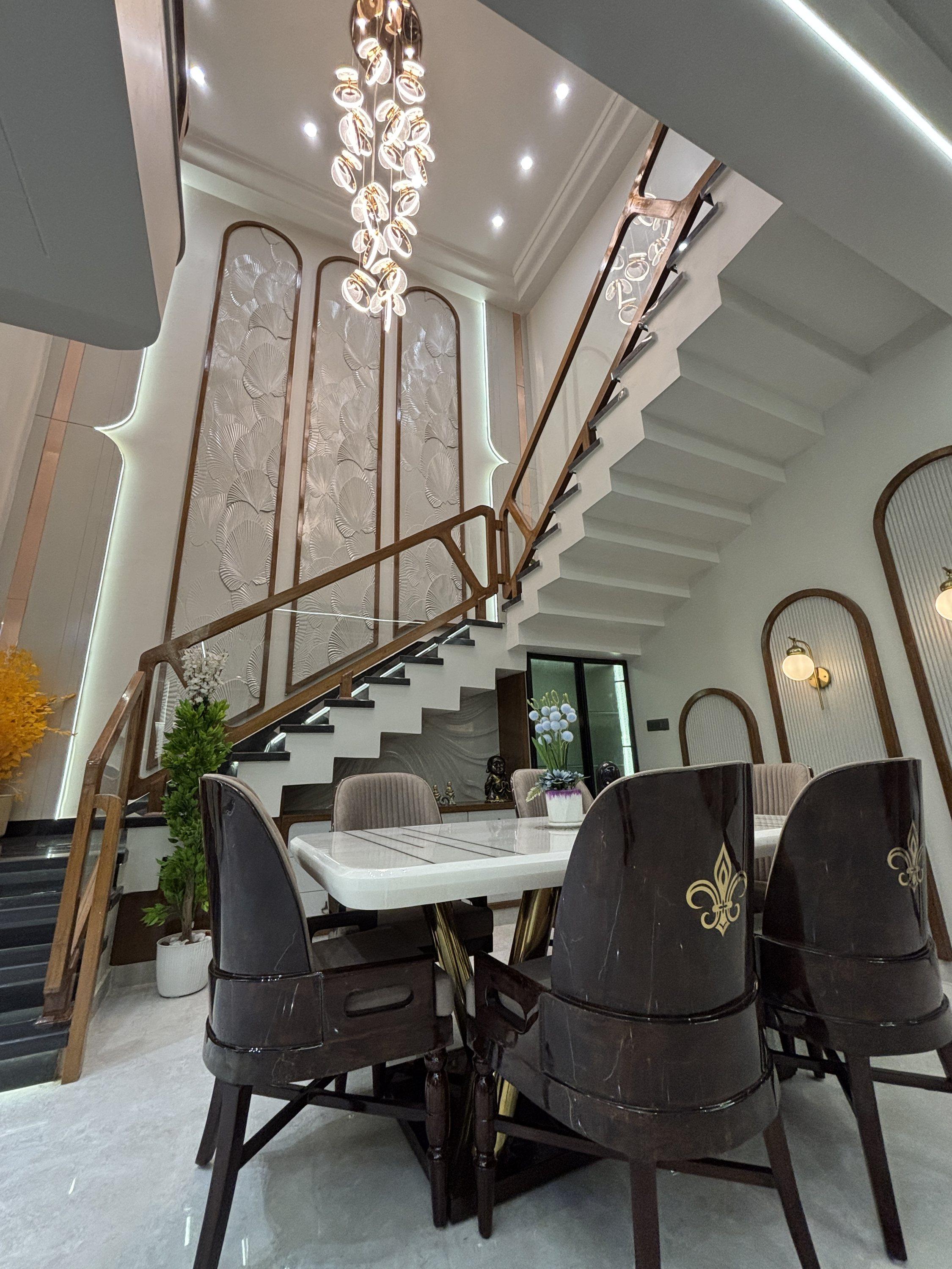 Dining area beneath a chandelier and staircase