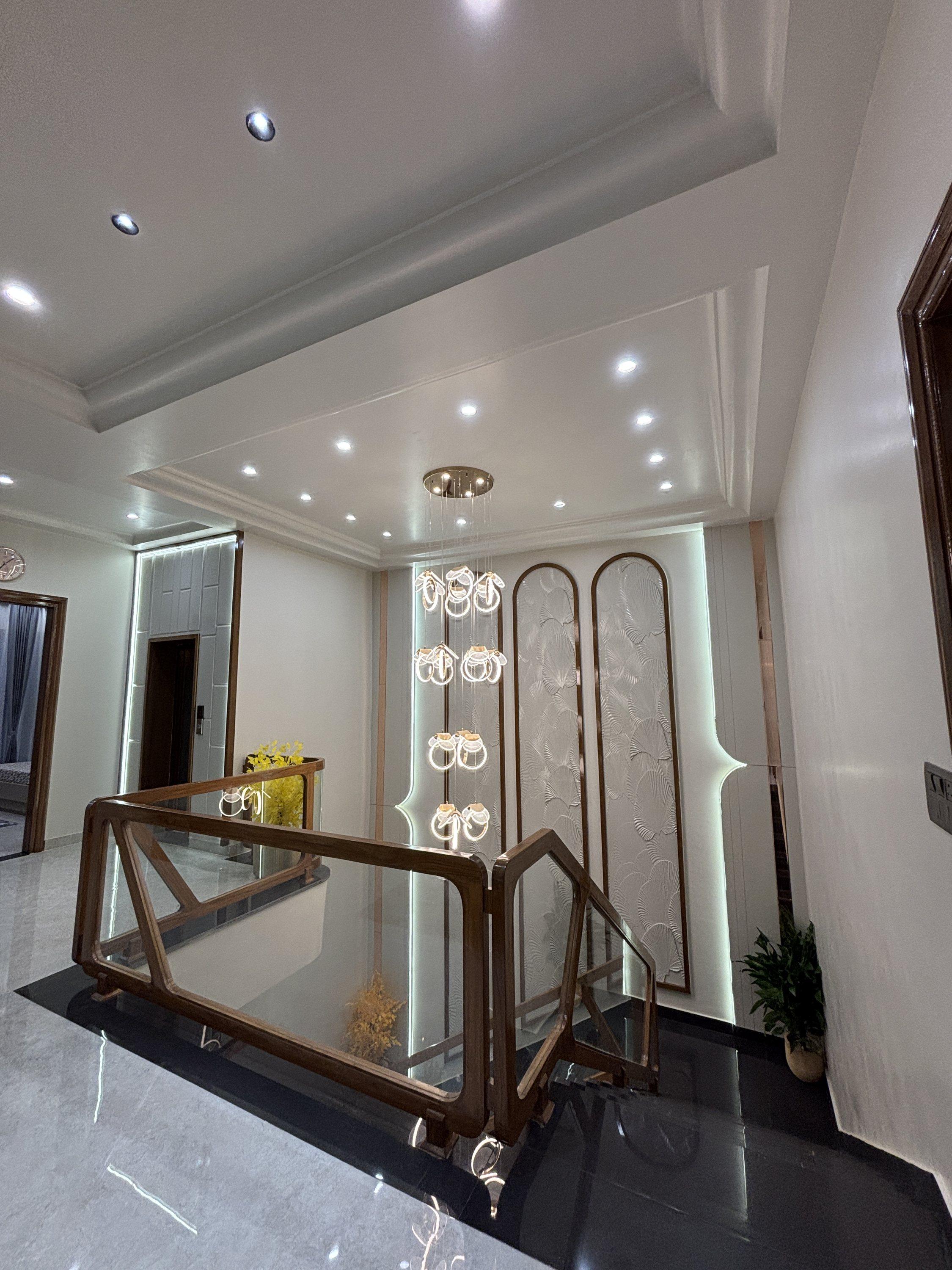 Staircase with glass railing and chandelier